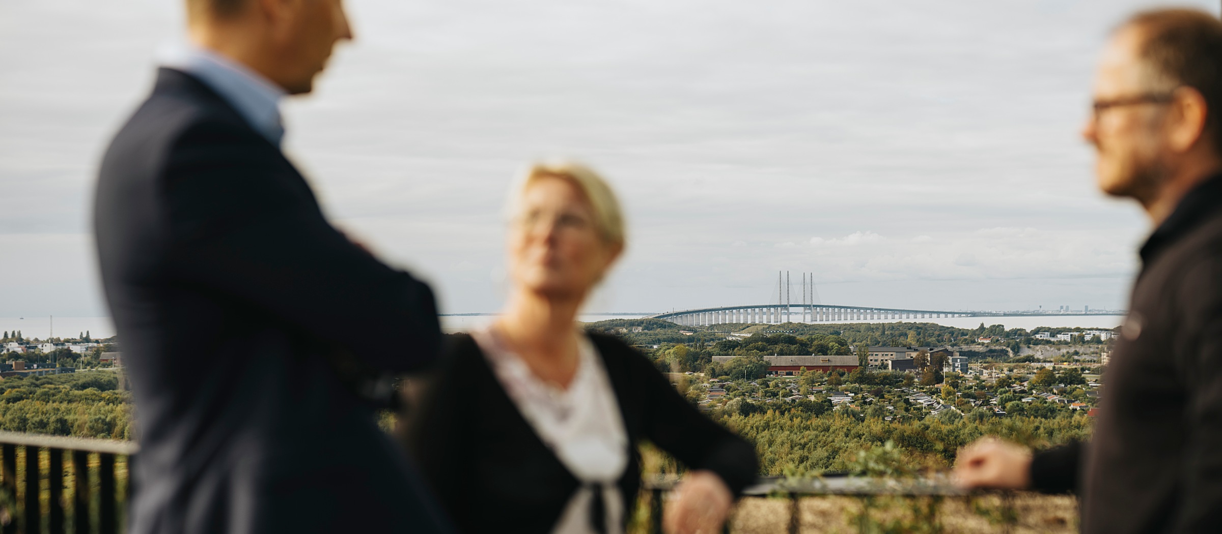 ”Wow! Det är omöjligt att inte slås av den”, säger AAK om utsikten, bland annat över Öresundsbron. Tre medarbetare i samtal med utsikt i bakgrunden.