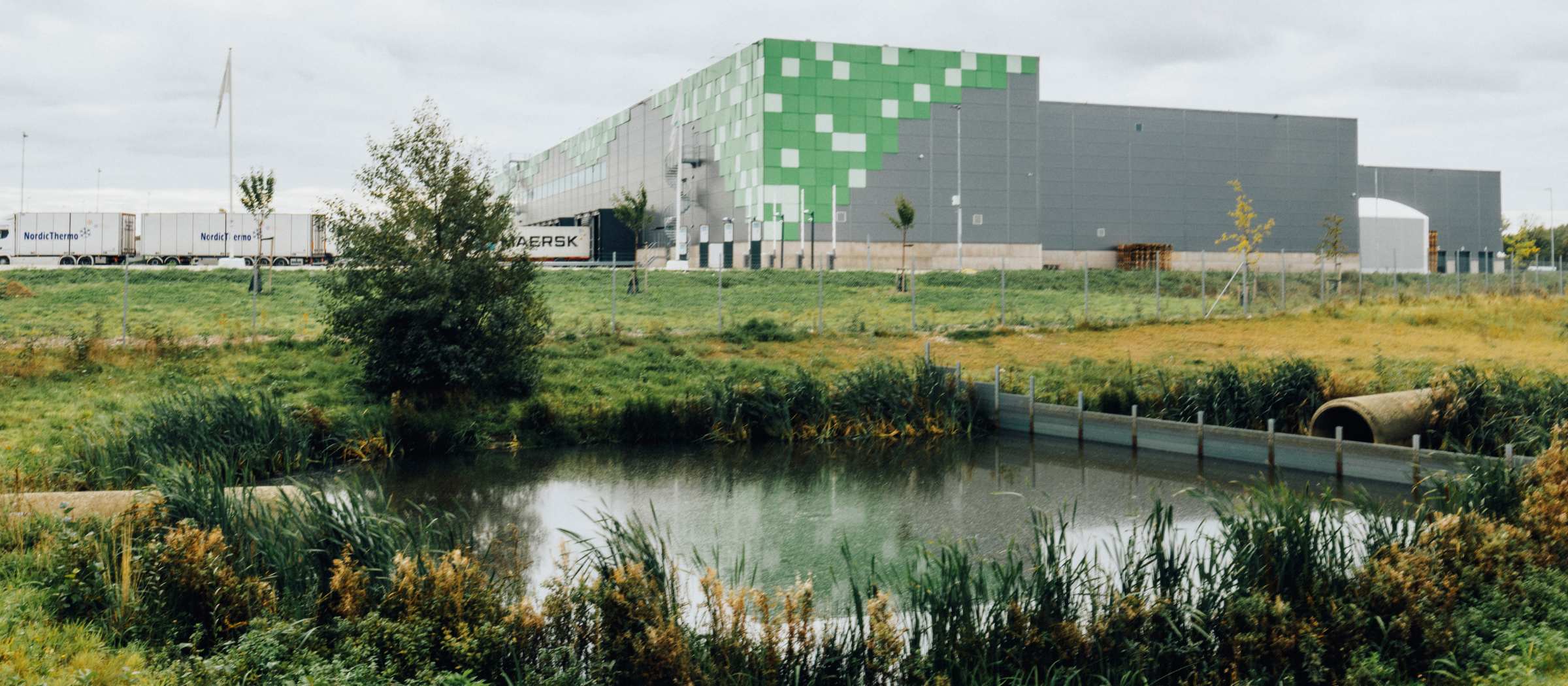 Anläggningen Greenhouse i Långeberga utanför Helsingborg har en stark grön profil, med bland annat solcellstak och planteringar för biologisk mångfald. Anläggningen Greenhouse med vattendrag och grönska i förgrundeen.